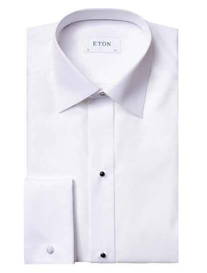 The Eton Pique Black Tie Tux Shirt, featuring a pointed collar and black buttons, is folded neatly with visible cuffs—making it an ideal choice for pairing with a tuxedo and bow tie at black-tie events.