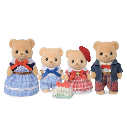 Four Calico Critters Biscuit Bear Family plush figurines, dressed in colorful outfits, stand in a row with a small toy castle in front of them—creating a delightful play set perfect for imaginative play and young design enthusiasts.