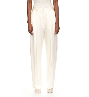 Model wears Victoria Beckham Wide Leg Trouser with a satin trim and a sleeveless white top, posed against a plain white background.