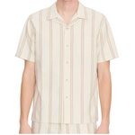 A person wearing the vince Cove Stripe SS Cabana—a short-sleeve, beige cotton-hemp shirt featuring a double-stripe pattern and a chest pocket—shown from the waist up against a white background.
