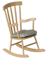 The Maileg Rocking Chair, Mouse - Wheat is a comfortable farmhouse-style wooden rocking chair featuring vertical slats on the backrest, a light yellow finish, and a blue patterned seat cushion.