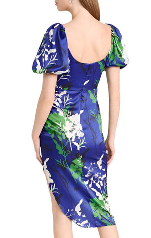 Back view of a woman wearing the Prabal Gurung Cowl Neck Side Ruched Dress; a blue, green, and white floral dress by Prabal Gurung, featuring short puff sleeves, an asymmetrical hemline, and a scoop back.