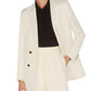 A person in a Blaze Milano Savannah Everyday Blazer, crafted from a white silk and linen blend, wears it double-breasted over a black shirt with one hand in the pocket against a plain background.