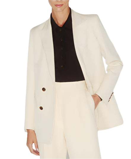 A person in a Blaze Milano Savannah Everyday Blazer, crafted from a white silk and linen blend, wears it double-breasted over a black shirt with one hand in the pocket against a plain background.