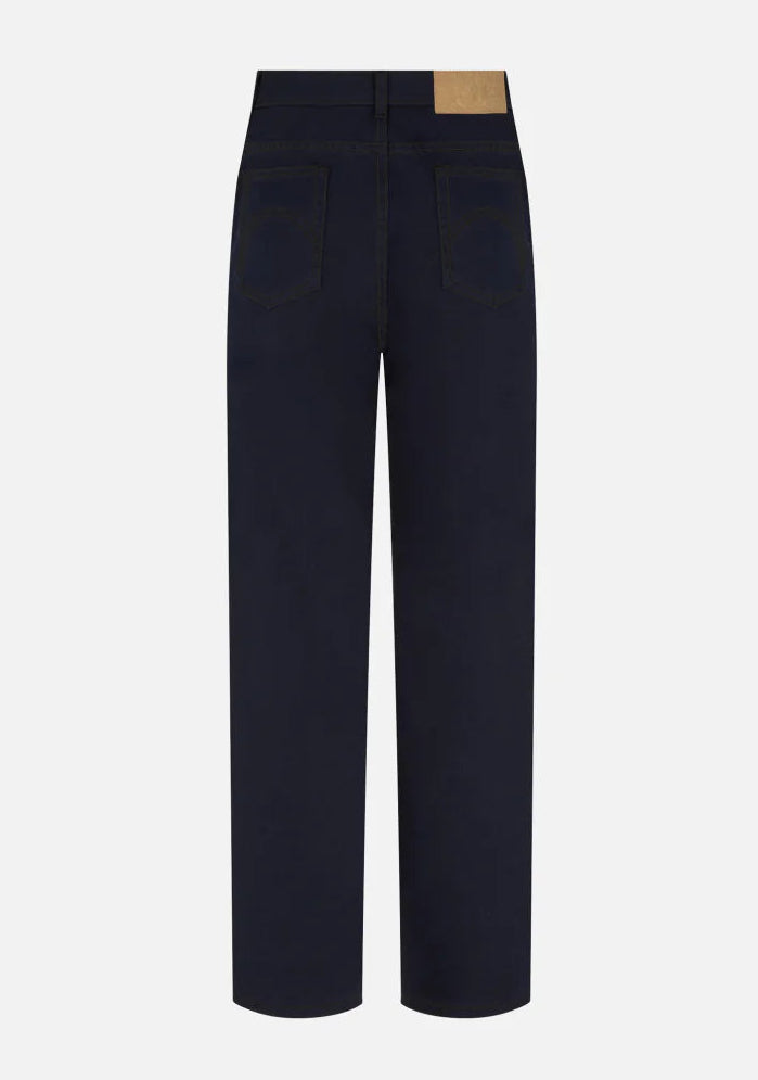 The Clapotis Paso Jeans by Blaze Milano are contemporary dark blue denim jeans, shown from the back, featuring two rear pockets, a high waist, wide legs, and a tan leather patch on the waistband.