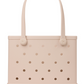 The Baby Bogg® Bag by Bogg Bags is a light beige, rectangular, customizable tote with circular holes, two handles, and “bogg” embossed on the lower right front. This washable and durable bag is ideal for everyday use and simple to keep clean.