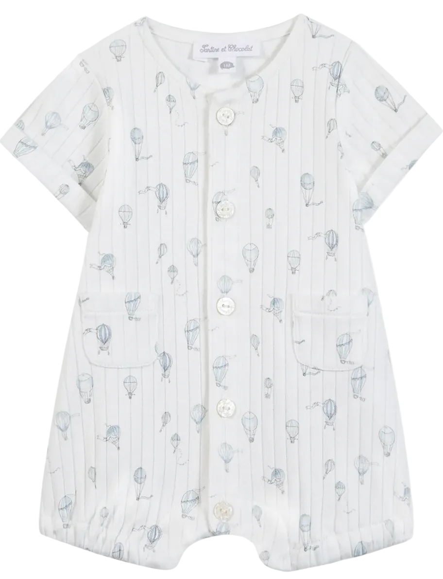 The Tartine et Chocolat Baby Boys’ Hot Air Balloon Short Jumpsuit features soft white cotton, short sleeves, front buttons, two pockets, and a subtle blue hot air balloon print—an ideal everyday newborn outfit that offers both comfort and style.
