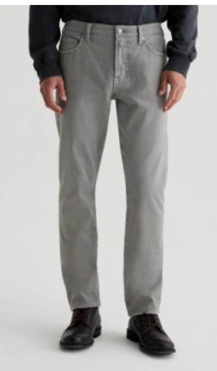A person wearing the Everett Slim Straight jeans in light gray by AG Jeans, styled with a black long-sleeve shirt and black lace-up boots, standing against a plain background.