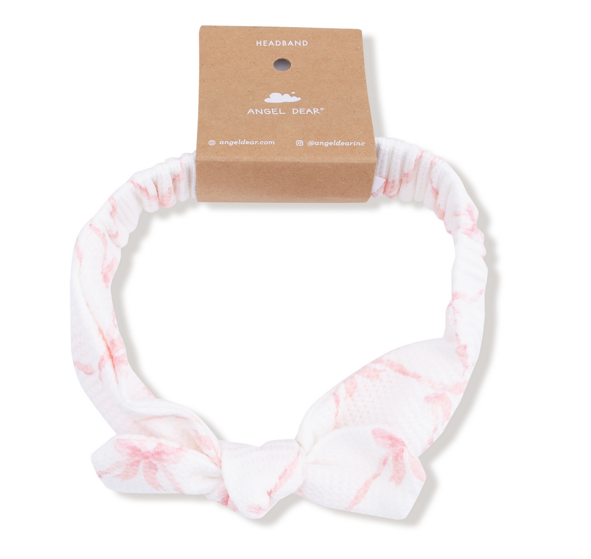 Angel Dear Knot Headband—white with light pink patterns, tied in a front bow. A cute baby accessory for fall and winter, displayed with a brown "Angel Dear" cardboard tag.