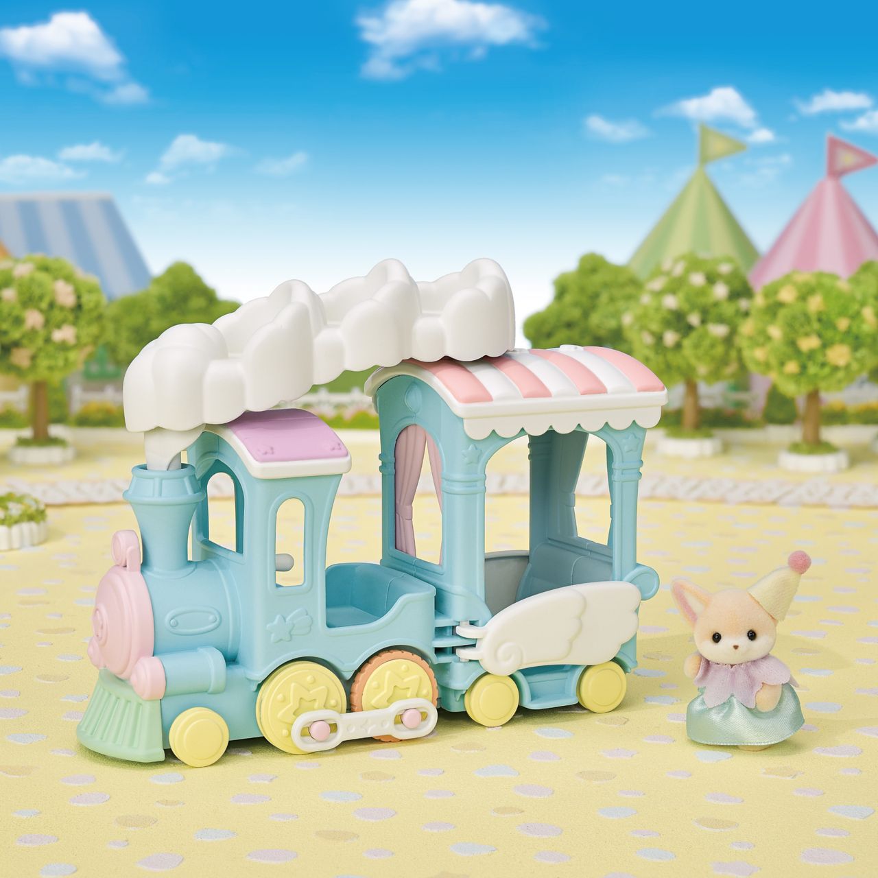 A Calico Critters Floating Cloud Rainbow Train, featuring pastel colors with cloud and wing details, is displayed outdoors on a playmat alongside a Calico Critters animal doll in a dress, creating an enchanting Amusement Park scene.