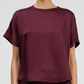 A model wears the Simkhai Addy Satin T-Shirt—short-sleeve, relaxed fit, burgundy with a round neckline—shown from shoulders to waist against a plain background.