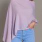 A person wears the Alashan Cashmere Cashmere Dress Topper Poncho in light purple with light blue jeans, standing against a neutral background.