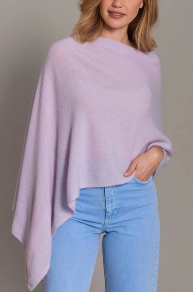 A person wears the Alashan Cashmere Cashmere Dress Topper Poncho in light purple with light blue jeans, standing against a neutral background.