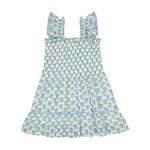 The Mer Girls' Paloma Dress is a sleeveless white dress featuring a blue and green tree print, with ruffled shoulder straps, a gathered bodice, twirly ruffle skirt, and a tiered ruffle hem, shown laid flat on a white background.