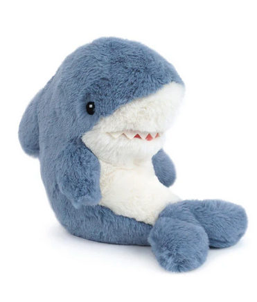 Meet the Mon Ami Tsunami Shark—a plush companion shaped like a blue shark with a white belly, black eyes, and small fabric teeth. This adorable stuffed sea creature sits upright on a white background.