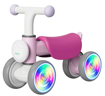 The Freddo Nature Navigator Balance Bike is a small pink and white ride-on for toddlers, featuring four wheels with colorful LED tire lights, thoughtfully designed for sensory discovery.