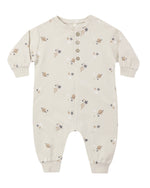 The Quincy Mae Baby Relaxed Fleece Jumpsuit is a beige long-sleeve onesie featuring a cozy fleece fabric, convenient button closure, and a space-themed print with planets, stars, and comets—an everyday essential designed for comfort.