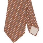 Sid Mashburn Silk Print Tie in orange, featuring a repeating geometric pattern of interlocking shapes in brown, white, and purple; this 8cm wide tie is pictured with the tip folded to display the reverse side.
