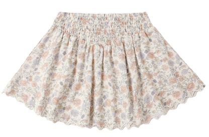 The Girls' Smocked V Mini Skirt by Rylee & Cru showcases a light floral pattern, smocked waistband, and scalloped hem. Pictured laid flat on a white background.