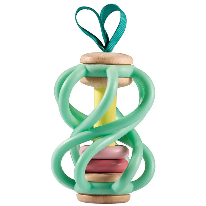 The Hape Apple Grab Toy features twisted green rubber sides, pink and yellow rings inside, wooden ends, and a green ribbon loop at the top for attaching to a stroller.
