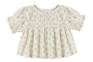 The Girls’ Colette Top by Rylee & Cru is a cream-colored, short-sleeved blouse adorned with a delicate floral pattern, gathered smocked detailing on the chest, and ruffled cuffs for a flattering fit.