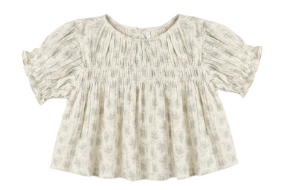 The Girls’ Colette Top by Rylee & Cru is a cream-colored, short-sleeved blouse adorned with a delicate floral pattern, gathered smocked detailing on the chest, and ruffled cuffs for a flattering fit.