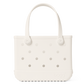 The Bitty Bogg® Bag by Bogg Bags is a white, rectangular tote featuring round side holes, sturdy handles, and the “bogg” logo embossed near the bottom corner. This compact tote is ideal for carrying daily essentials, and its washable design ensures easy cleaning and long-lasting durability.