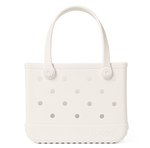 The Bitty Bogg® Bag by Bogg Bags is a white, rectangular tote featuring round side holes, sturdy handles, and the “bogg” logo embossed near the bottom corner. This compact tote is ideal for carrying daily essentials, and its washable design ensures easy cleaning and long-lasting durability.