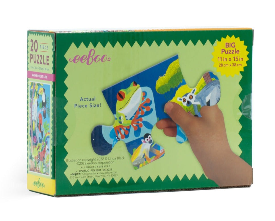 Box containing the Eeboo Rainforest Life 20 Piece Puzzle, showcasing vivid animal illustrations and a hand holding a puzzle piece. This educational toy engages young minds, inspiring curiosity about the wonders of rainforests, making it an ideal children's puzzle.