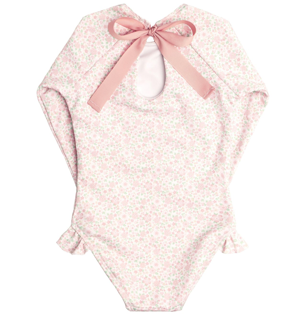 A pink floral-patterned baby onesie with long sleeves, an open back, a pink bow at the top, and ruffle hip detail. Made from buttery soft fabric for ultimate comfort is Minnow Girls' Rashguard One Piece by Minnow.