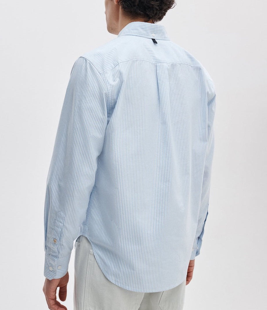 A person is seen from the back against a plain light background, wearing the Rag & Bone Classic Oxford Shirt in light blue and white stripes with a classic fit.