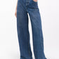 Person wearing Rag & Bone Miramar Terry Sofie Full high-waisted wide-leg blue jeans with white pointed-toe shoes, posed against a plain light background.