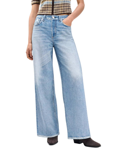 Person wearing Rag & Bone Miramar Terry Sofie Wide Pant, a striped short-sleeve top, and black heeled boots, with hands in the pant pockets.