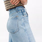 A person shown from the side and waist down wearing Rag & Bone's Miramar Terry Sofie Wide Pant in light blue with a brown and green striped sleeveless top.