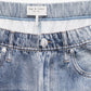 Close-up of the Miramar Terry Wide Track Pant by Rag & Bone, featuring blue denim-look fabric, silver button, pockets, a "rag & bone NEW YORK" label, and a hint of elastic waistband for comfort.