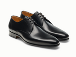 The Magnanni Maddin Lace-Up is a pair of black calfskin plain toe derby dress shoes with laces and low heels from the Línea Flex collection, shown on a white background.