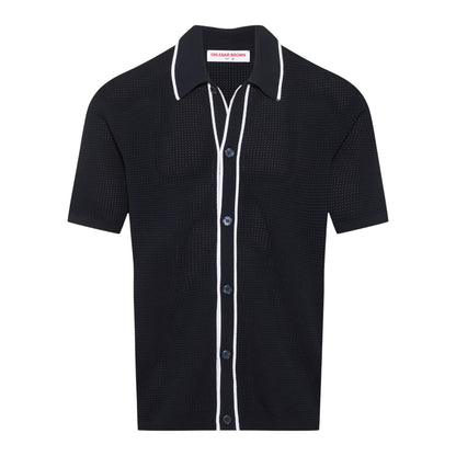 The Orlebar Brown Roddy Button Through Knitted Shirt is a short-sleeve black waffle mesh style with white piping at the collar, placket, and pocket seams, finished with textured summer tailoring and a "Chelsea Brown" label inside.