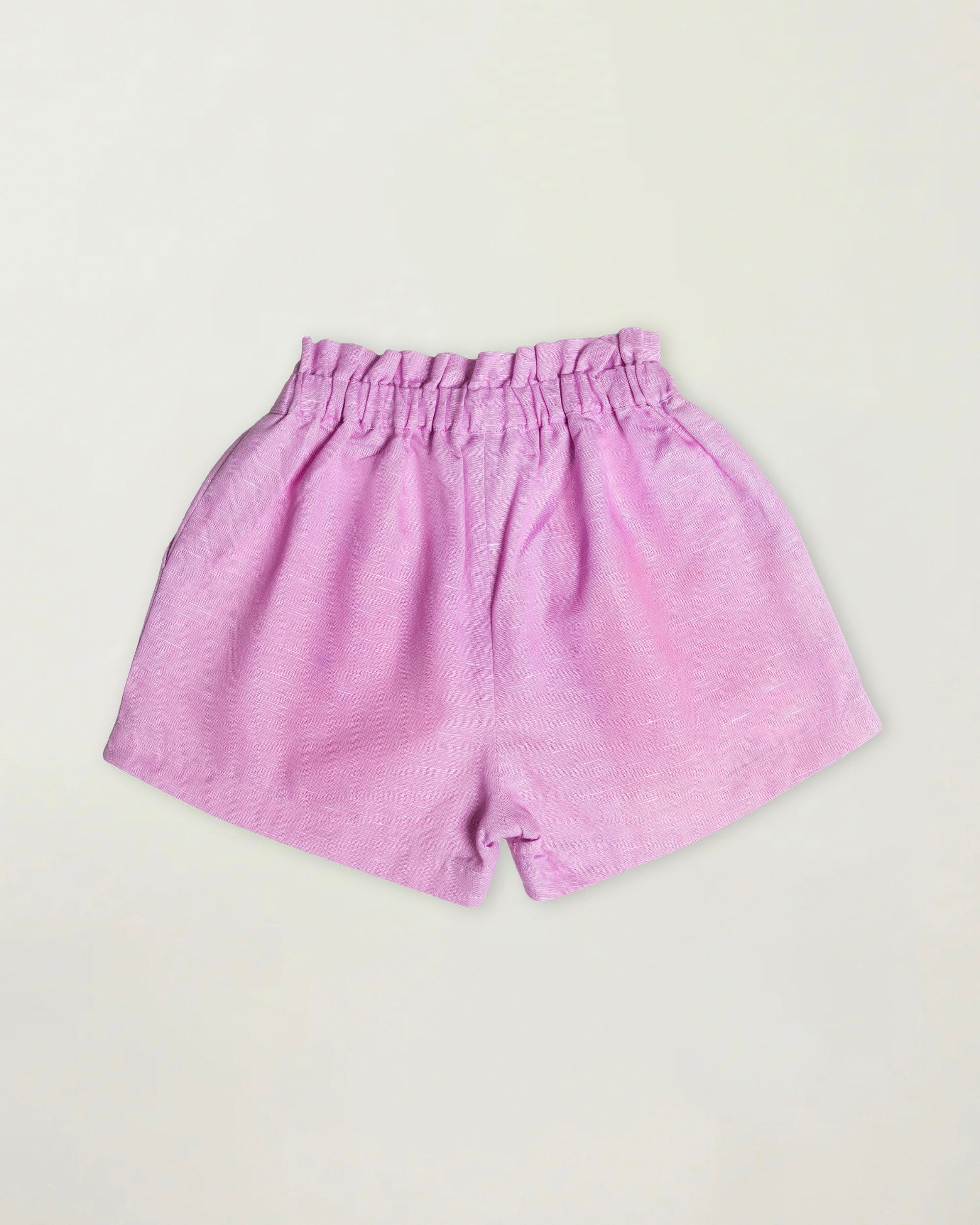 Early Sunday Girls’ Roman Shorts in light pink cotton-linen feature an elastic waistband for comfort and easy wear. Displayed flat on an off-white background, these breathable shorts combine everyday style with play-ready ease—ideal for active kids.
