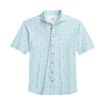 The Johnnie-O Rowing Shirt is a light blue, short-sleeve button-up featuring a subtle small pattern inspired by surf culture, wooden buttons, and a collar, displayed laid flat on a white background.