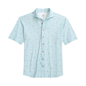 The Johnnie-O Rowing Shirt is a light blue, short-sleeve button-up featuring a subtle small pattern inspired by surf culture, wooden buttons, and a collar, displayed laid flat on a white background.