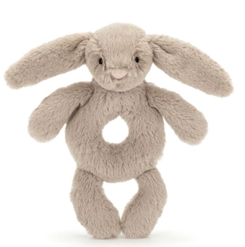 A plush gray bunny toy with large floppy ears, known as the Jellycat Bashful Beige Bunny Ring Rattle, and a hole in its midsection.