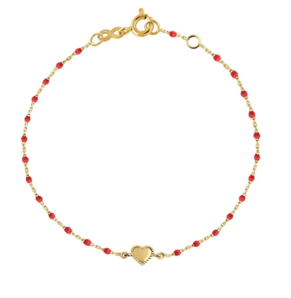 The Mini Lucky Heart Bracelet 6.7" by Gigi Clozeau showcases an elegant 18-carat gold band with vibrant red beads, highlighting its heart-shaped charm.