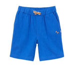 The Boys' Cotton Rustic Bermuda Short by Arsene & Les Pipelettes is crafted from textured cotton in a vibrant blue, featuring an elasticated waist with a small decorative bow at the center and "AP" embroidery on one side pocket.
