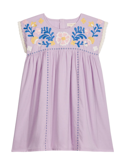 The Girls’ Talula Dress by Louise Misha is a lavender sleeveless dress made from soft cotton veil, adorned with floral embroidery on the chest, delicate lace trim on the shoulders, and blue stitched lines running vertically down the front.
