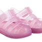 The Igor Girls' Star Jelly Sandal features translucent pink PVC with glitter, closed toes, side straps, and a removable foot bed.