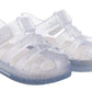 The Igor Girls' Star Jelly Sandal features translucent PVC with silver glitter, closed toes, adjustable ankle straps, textured soles, and classic water sandal comfort.
