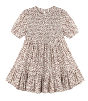 The Girls’ India Dress by Rylee & Cru features short sleeves, a knee-length silhouette, a light brown floral pattern, a smocked bodice, gathered waist, and a ruffled hem.