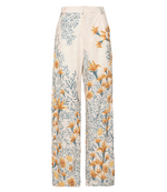 The Florecer Pant by Agua By Agua Bendita is a wide-leg, high-waisted trouser with a cream base, yellow floral print, blue and green leaves, and dotted patterns.