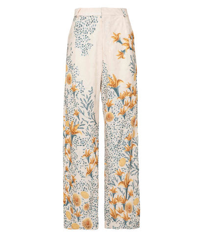 The Florecer Pant by Agua By Agua Bendita is a wide-leg, high-waisted trouser with a cream base, yellow floral print, blue and green leaves, and dotted patterns.