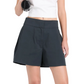 A person in a white crop top and Proenza Schouler White Label's Natalia Short holds a rolled-up yoga mat against a plain white background, highlighting the sporty style of these classic high-waisted shorts.